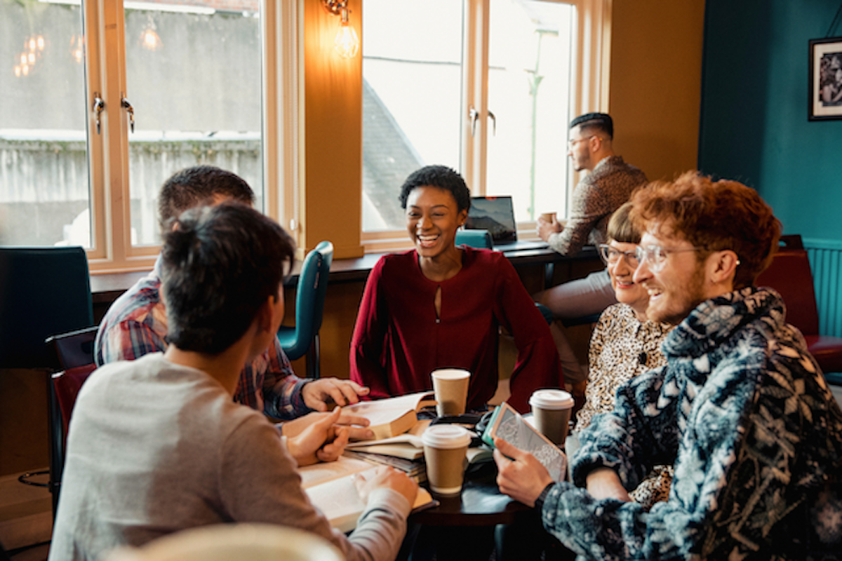 Group of people discussing over books and coffee.