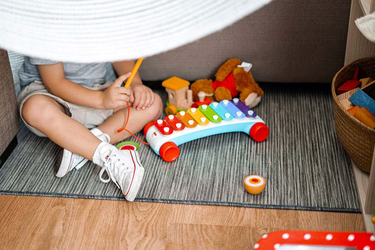 Bottom half of a kid seen with xylophone and other toys