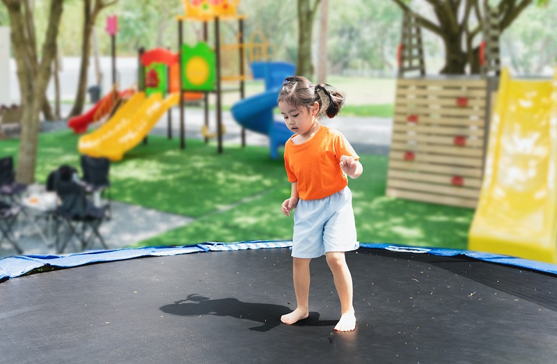 Kid jumping on a trampoline in a park