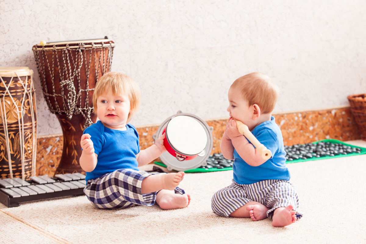 Two babies sitting with drums.