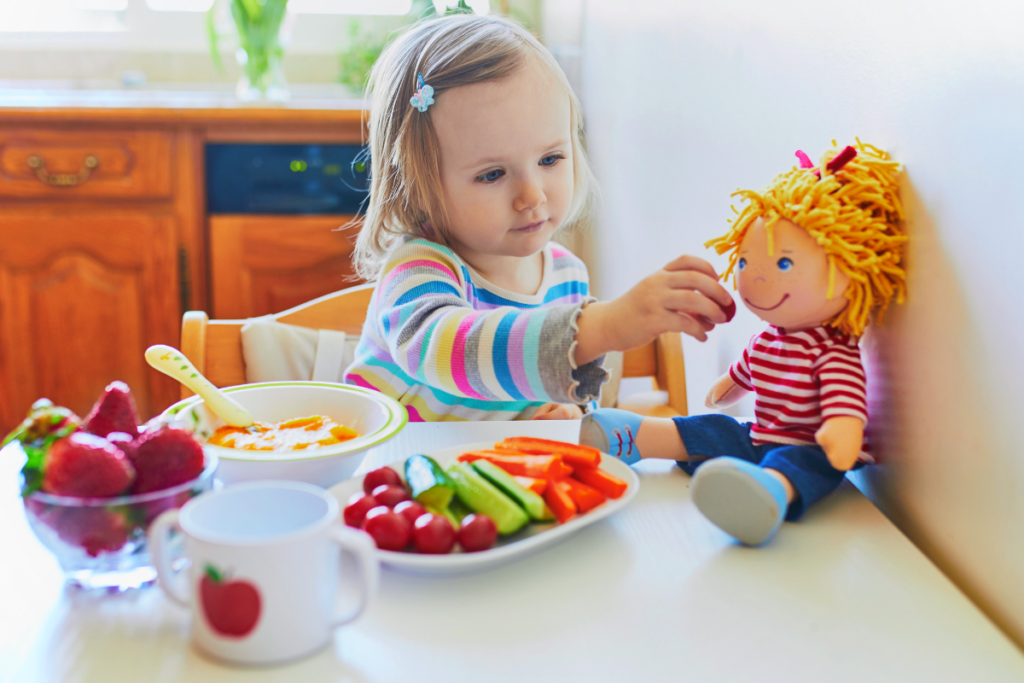 A kid making her doll eat vegetables