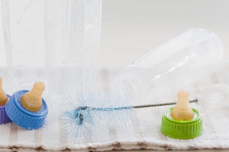 Baby bottles are drying on a towel after being washed.