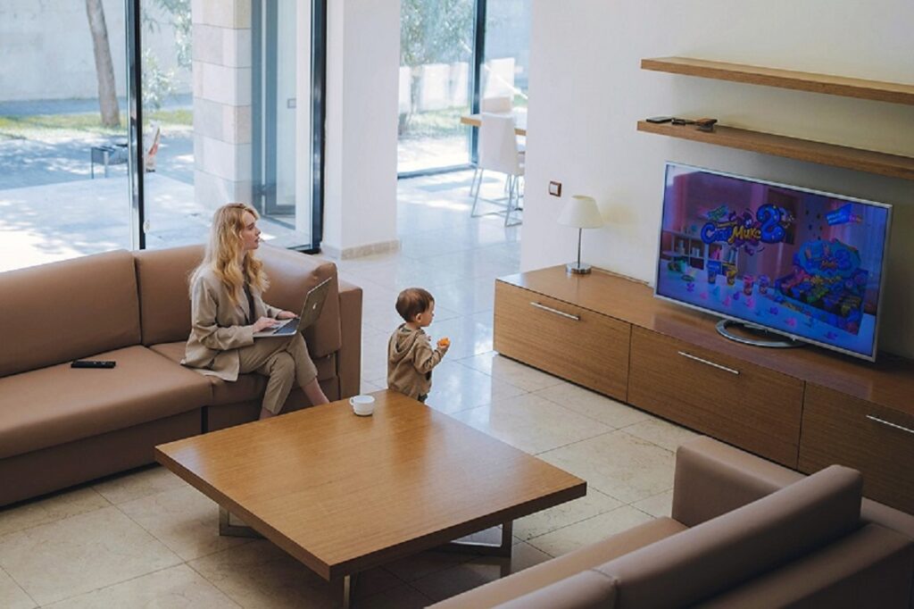 an adult and a kid in a TV lounge watching TV