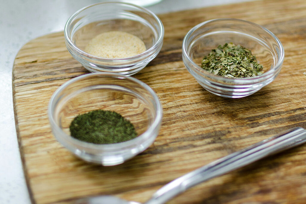 different herbs in a bowl placed on a wooden table