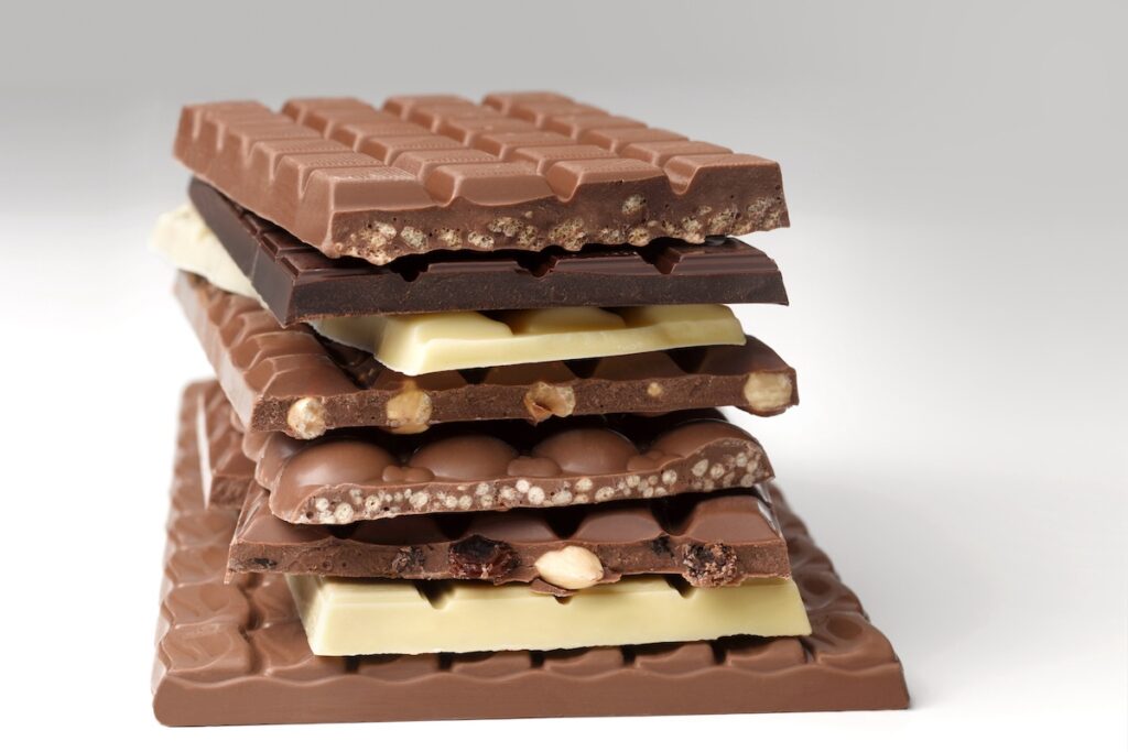 A stack of milk, white, and dark chocolate bars on a white background.