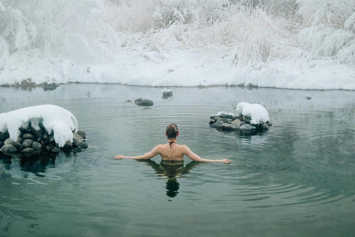 A person taking a cold plunge in freezing river.