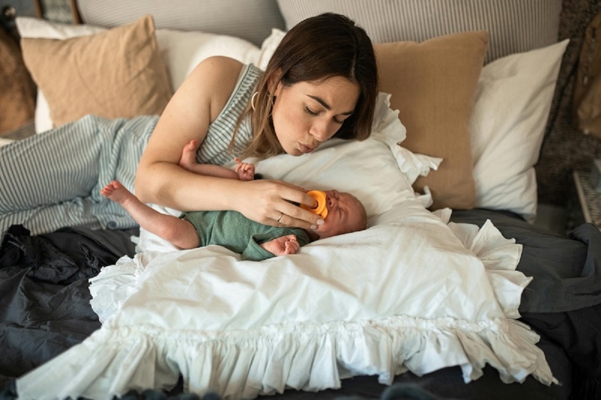 a parent giving pacifier to baby and trying to sleep