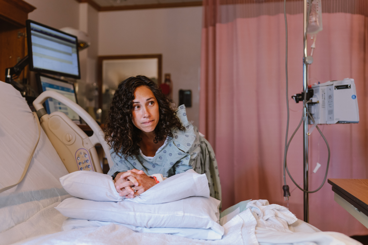 Woman leaning on hospital bed