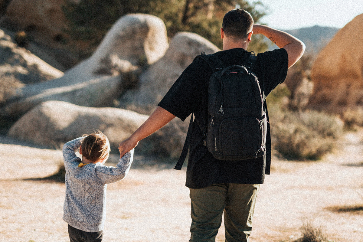 a parent and a son standing outdoor and looking for something in the sunlight