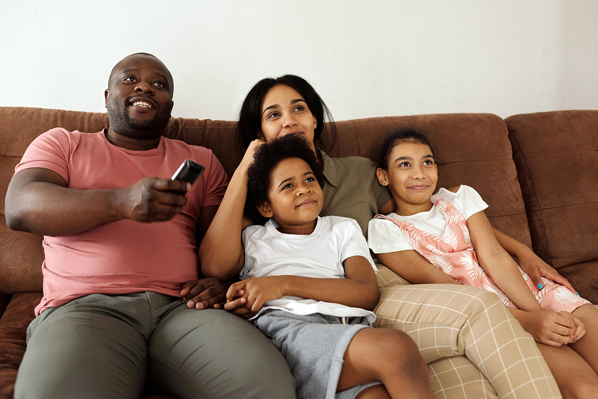 parents and kids sitting on sofa and watching movie