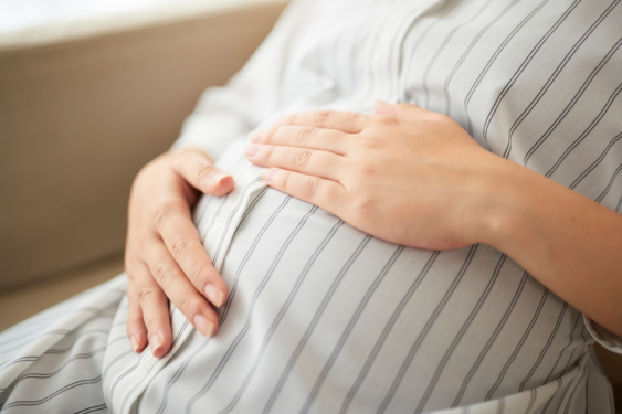 A pregnant person touching her belly.