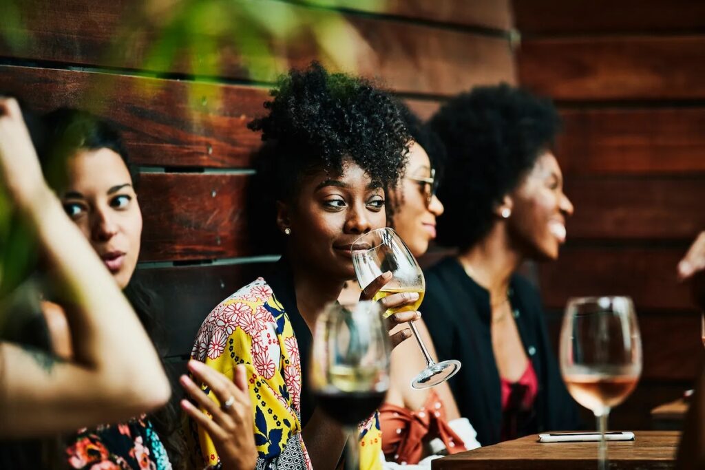 A woman sips a glass of wine with friends.
