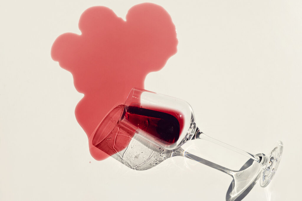 A glass of red wine spilled on a white background.