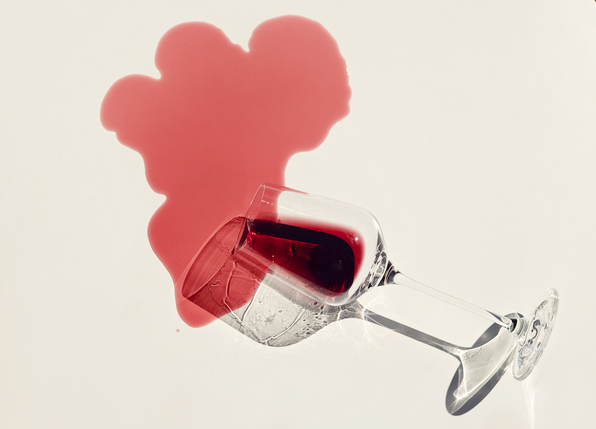 A glass of red wine spilled on a white background.