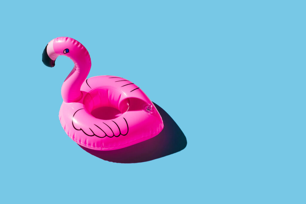 A pink inflatable flamingo on a blue background.