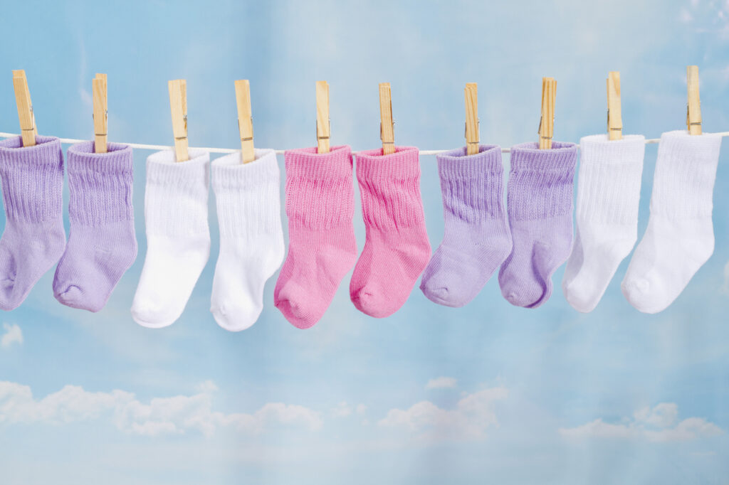 Colorful pairs of baby socks hanging on a clothesline.