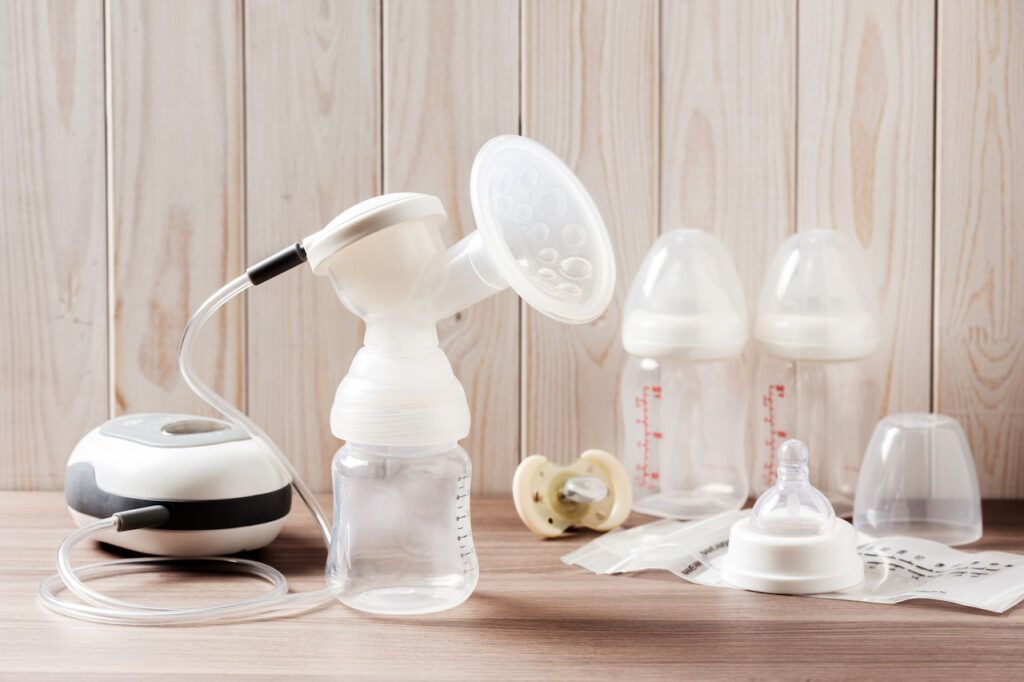 A breast pump set with no milk is set out on a wooden table.