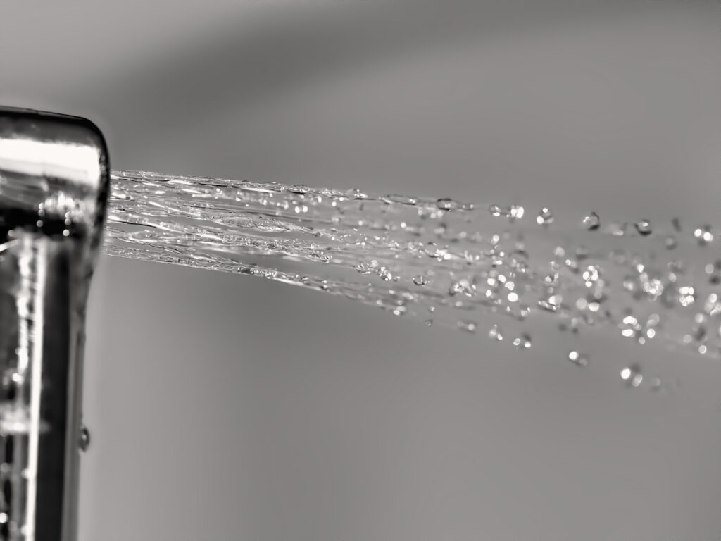 Water sprays from a bidet against a gray background.