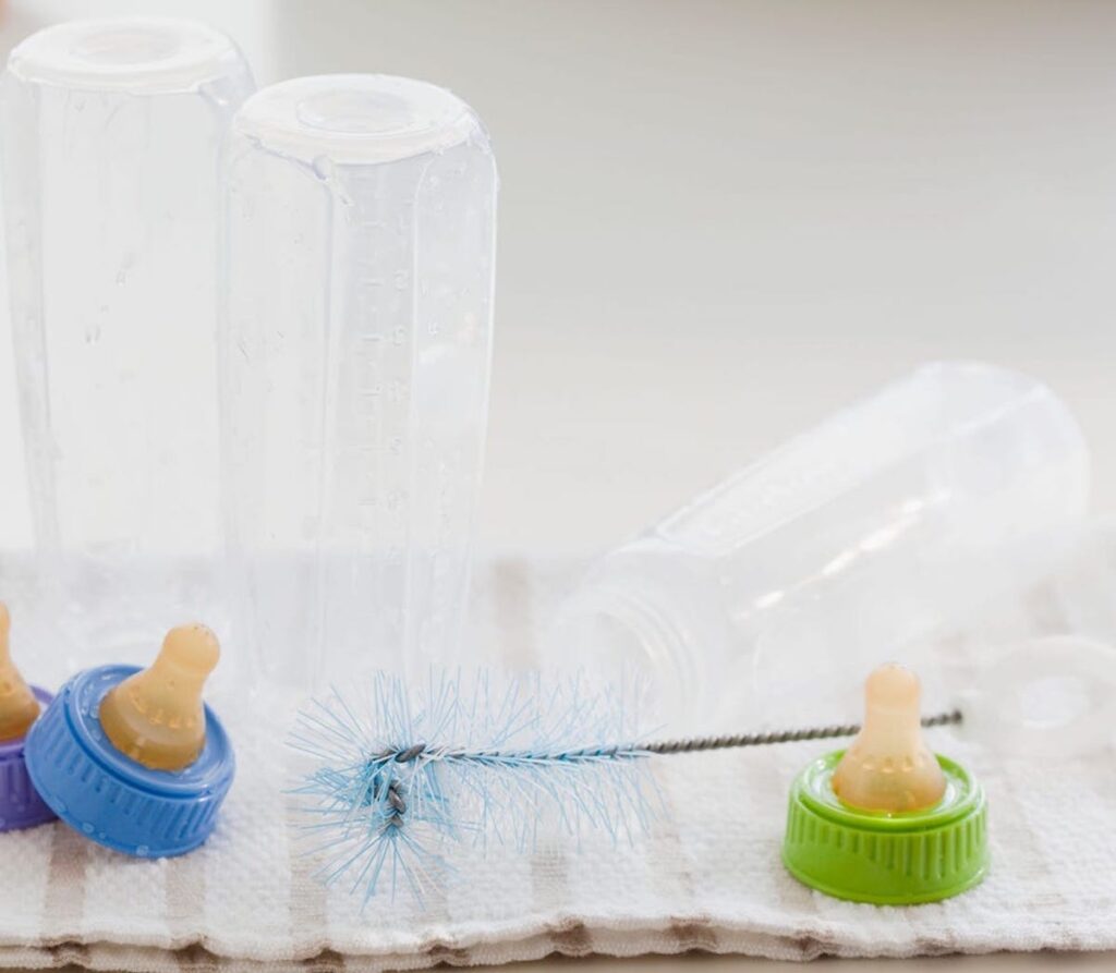 Baby bottles are drying on a towel after being washed.