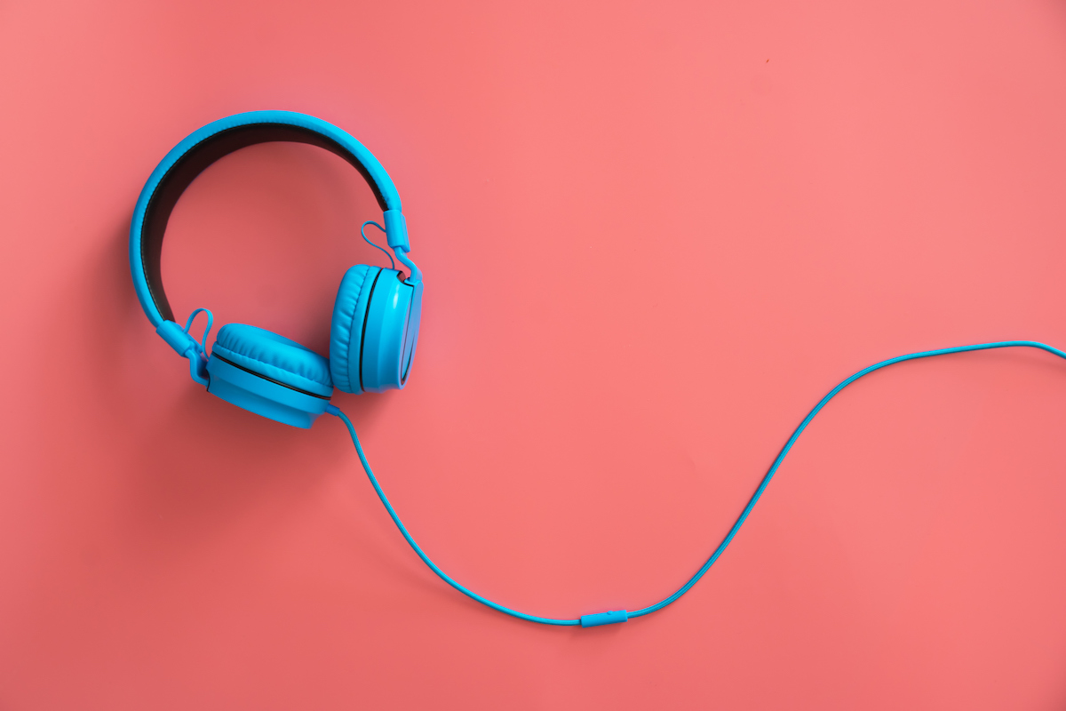 Large blue headphones on a pink background.