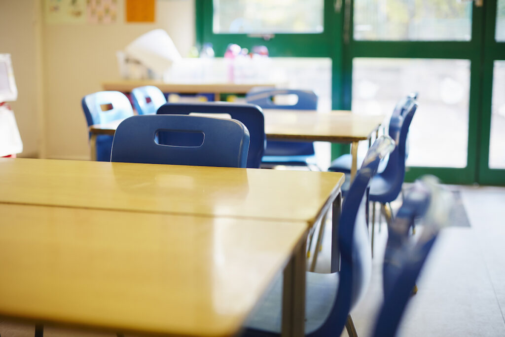 Empty school desks are seen in a crowded classroom.