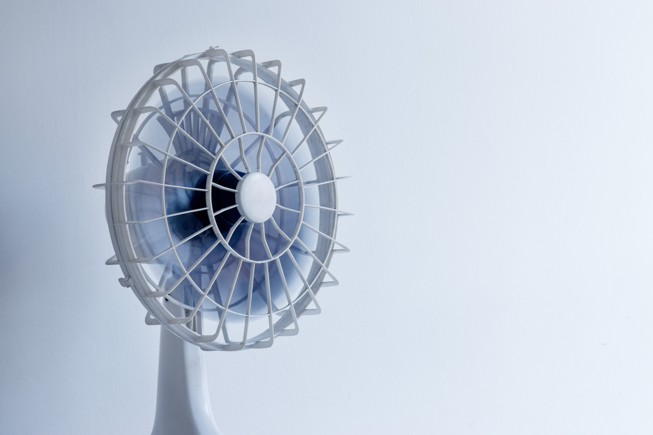 A white electric fan against a gray background.