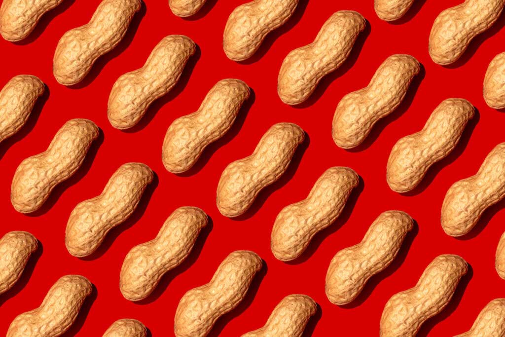Peanuts are arranged in rows on a red background.