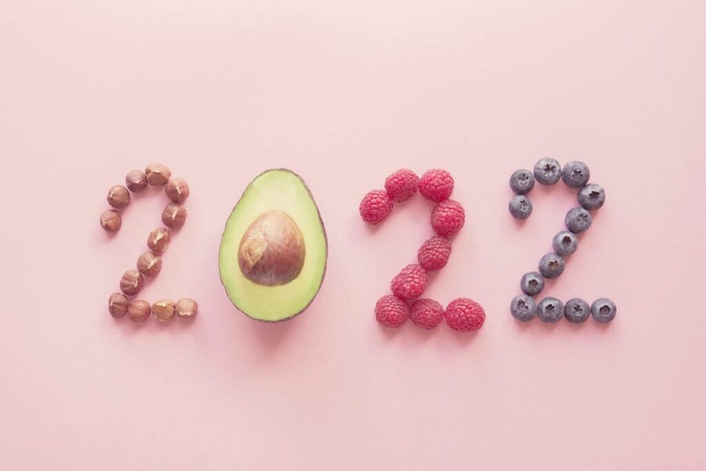 Nuts and berries are arranged to spell out "2022" on a pink background.