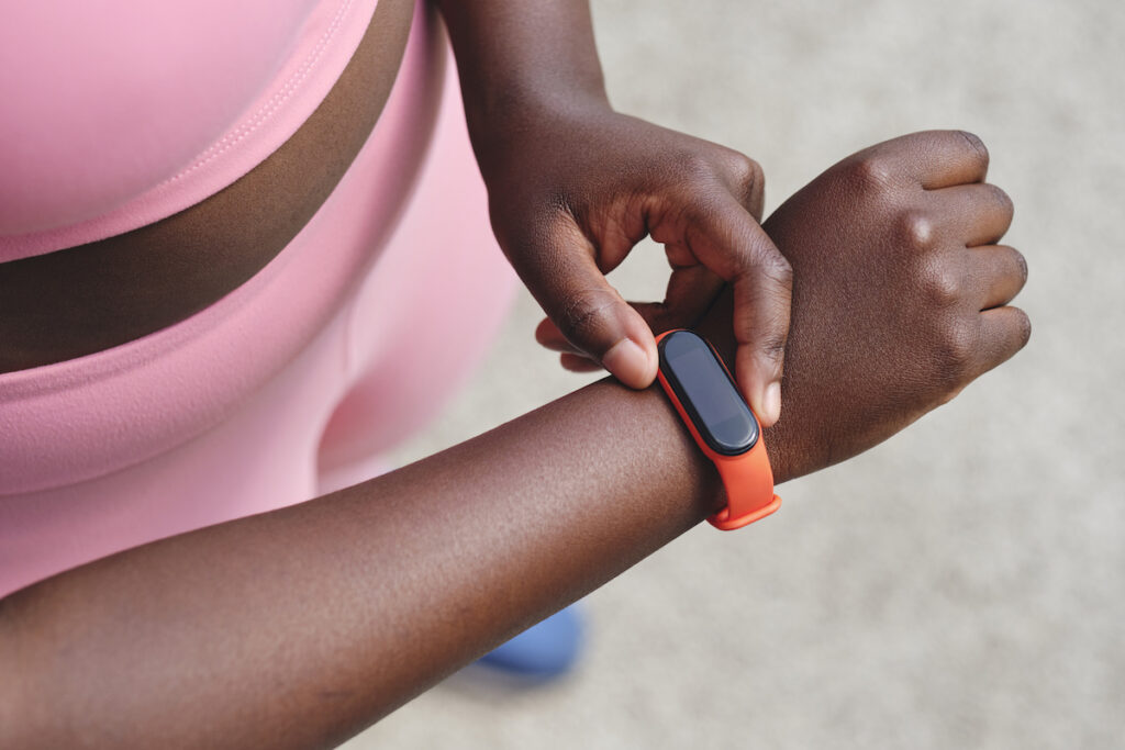 A woman wearing pink athletic clothes check her fitness watch.