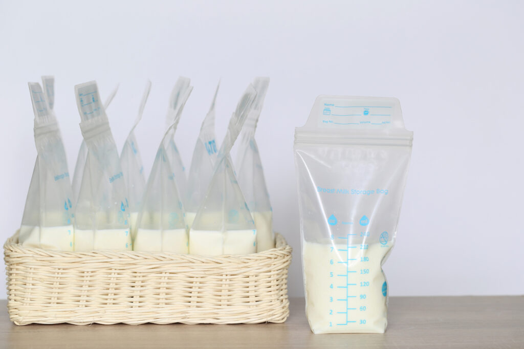 Frozen bags of breastmilk are arranged in a wicker basket on a table.