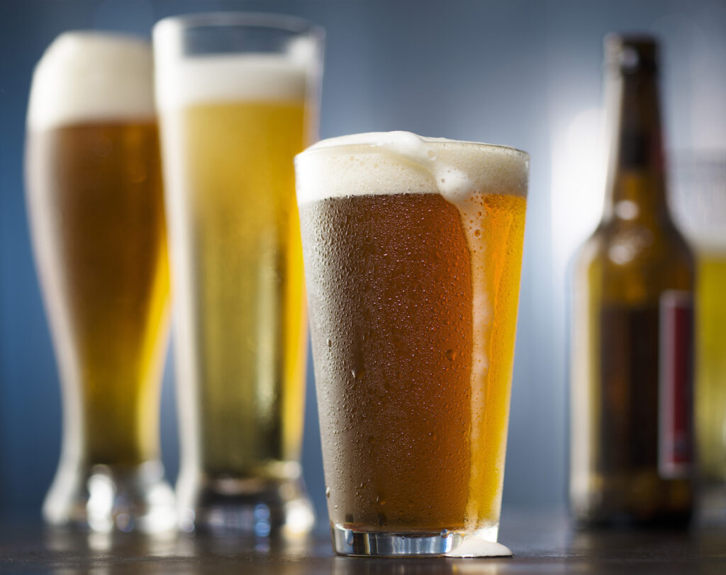 Glasses of beer are seen against a gray background.