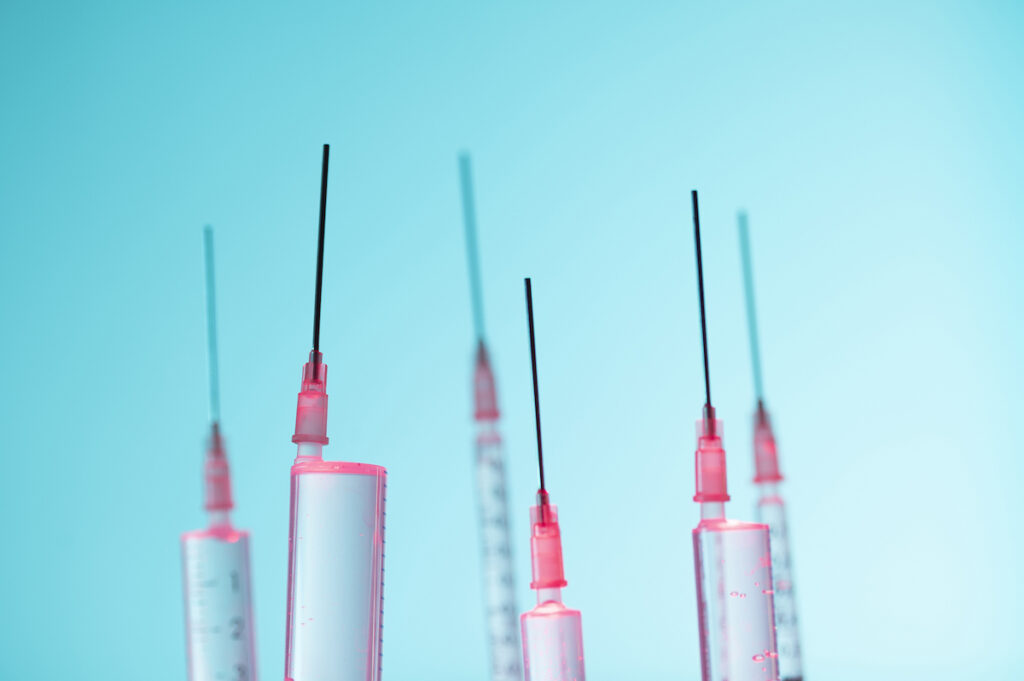 Epidural syringes point up agains a blue background.