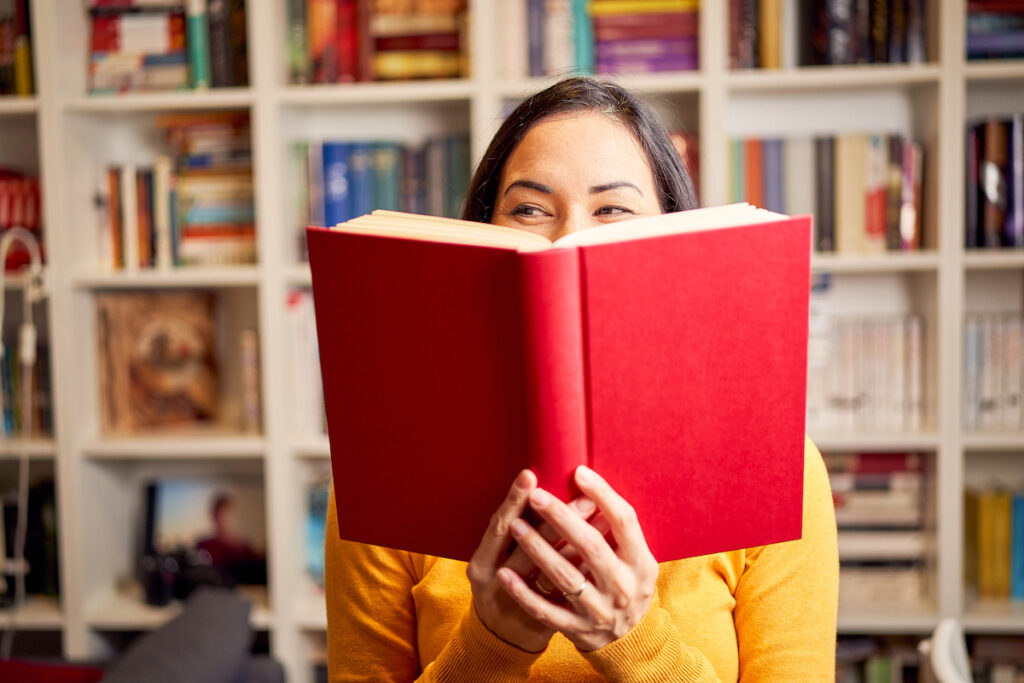 A reader holds a book in front of their face.