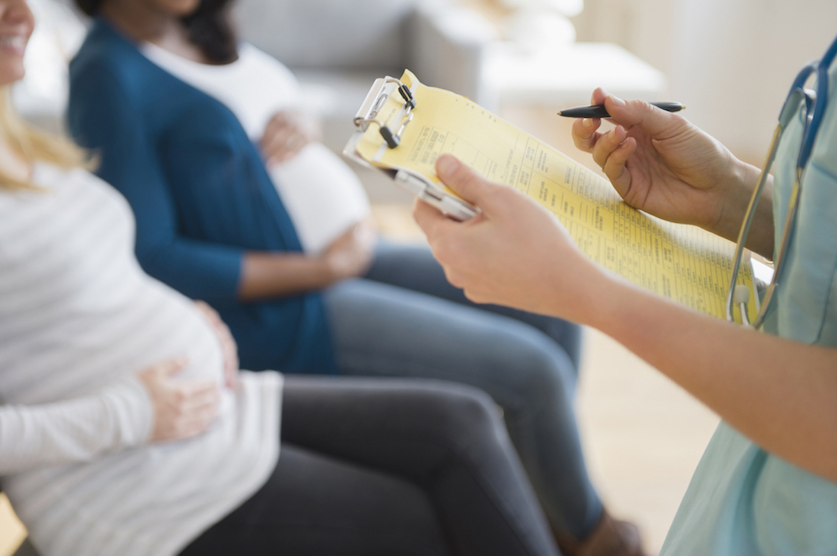 Three pregnant people are seated in a row in a doctor's office waiting room. A nurse holds a yellow checklist.