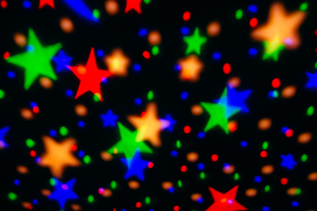 Colorful projections of stars from a child's nightlight on a dark background.