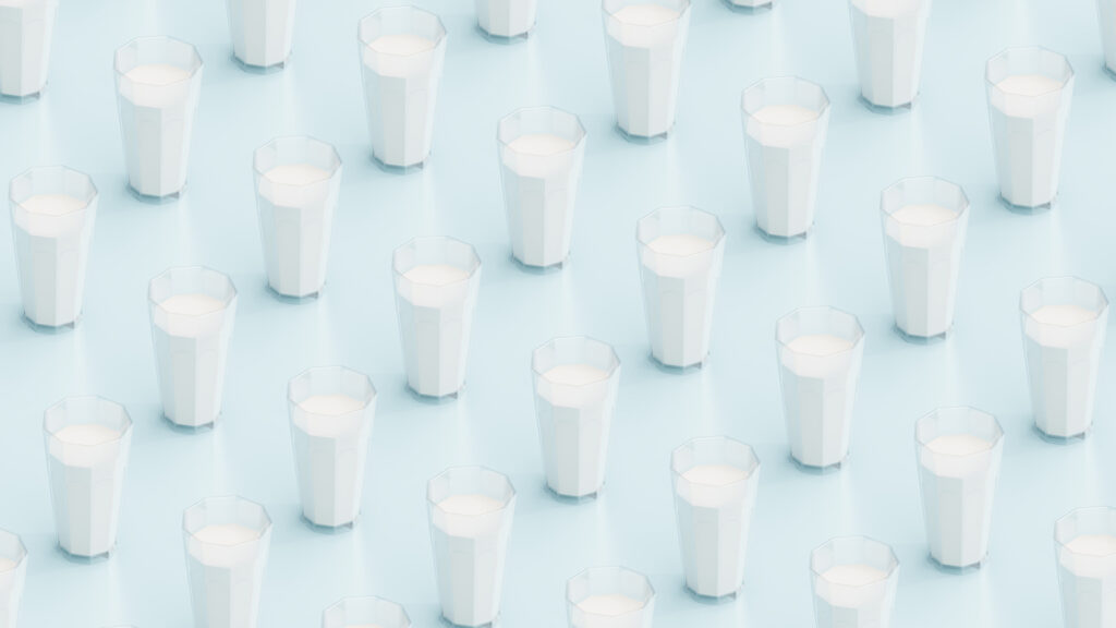 Diagonal rows of glasses filled with milk are seen on a light blue background.