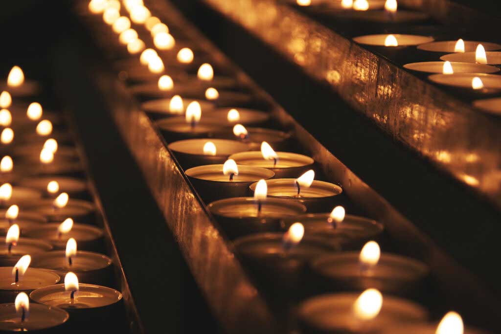 A group of lit candles is seen in the dark.