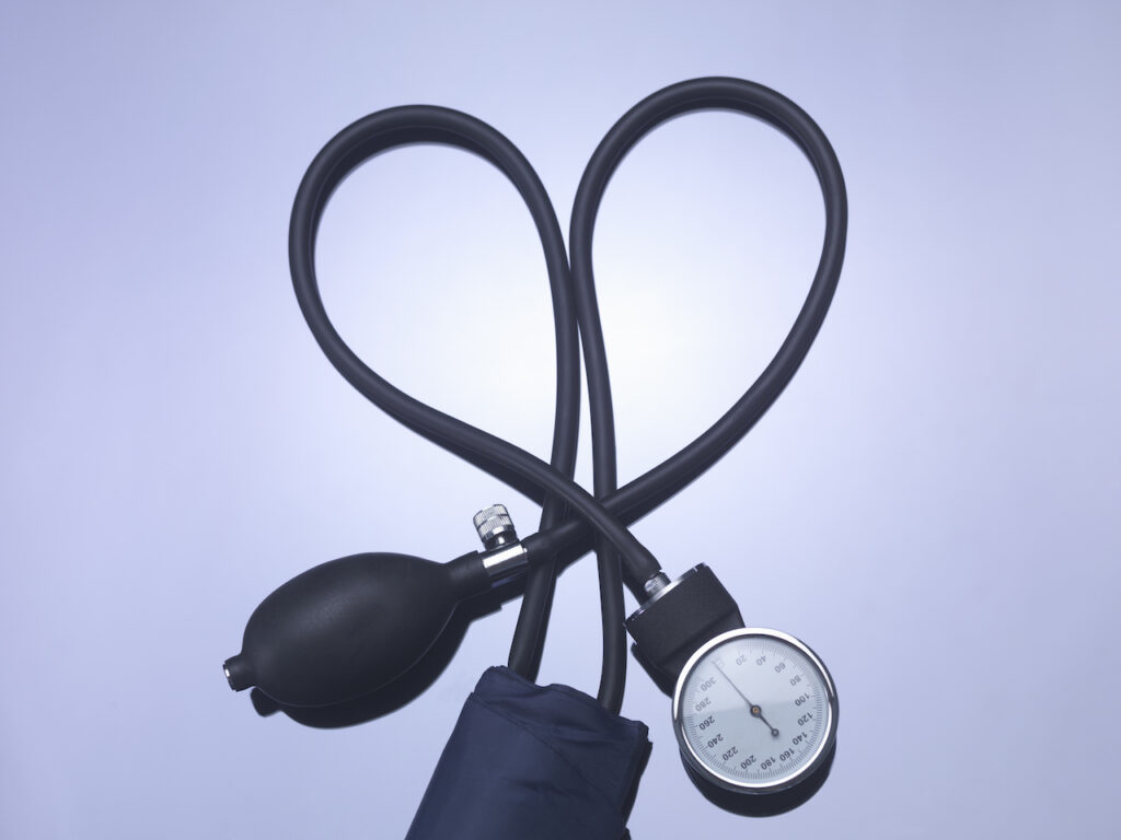 A blood pressure gauge and pump are arranged on a gray background.