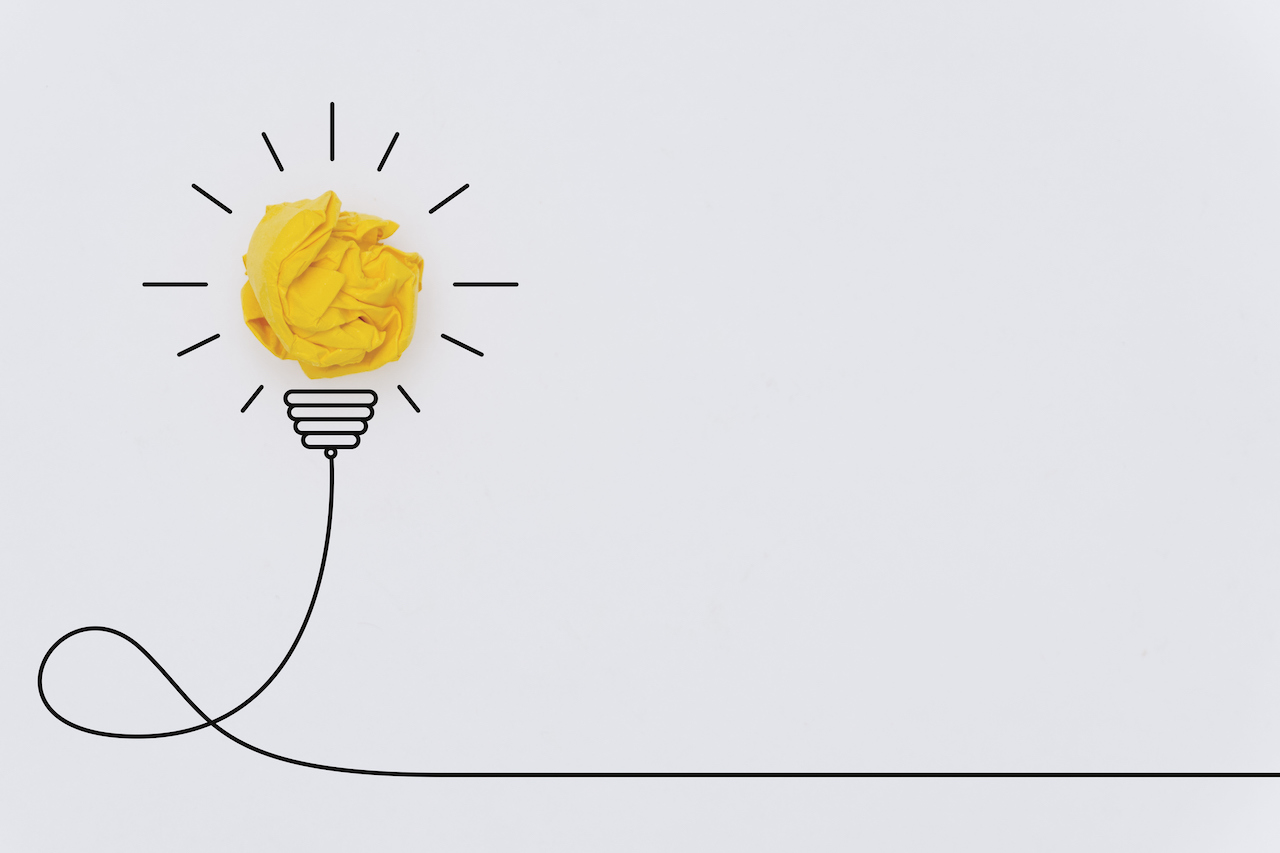 A lightbulb is made of crumpled yellow paper, with the other parts of the lightbulb drawn by hand.
