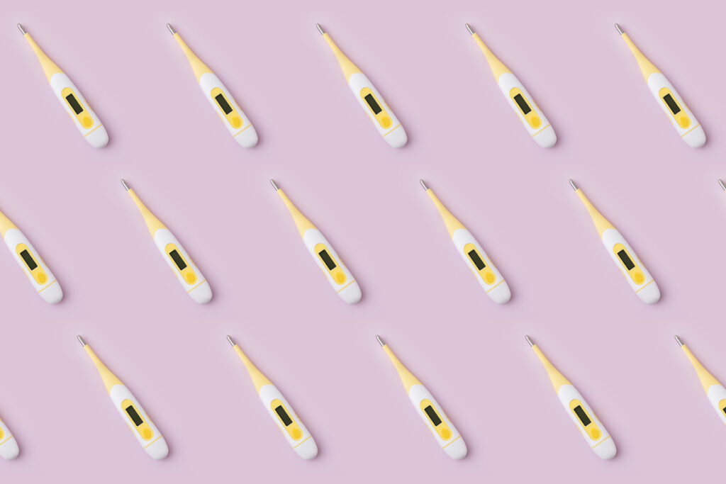 White and yellow digital thermometers are arranged in rows on a pink background.