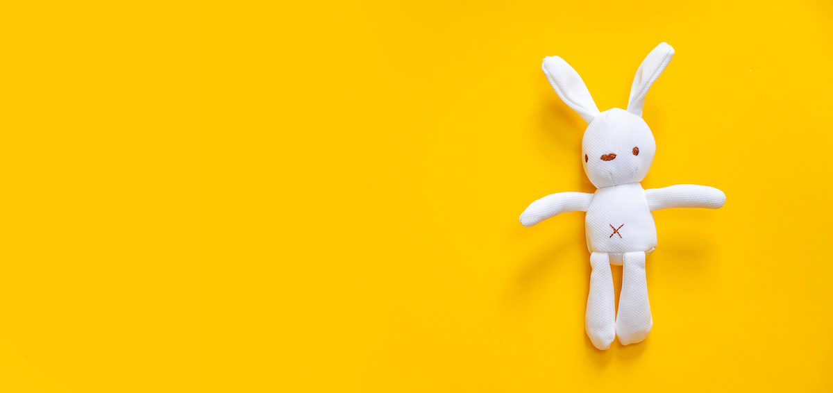 A white stuffed bunny is pictured against a bright yellow background.