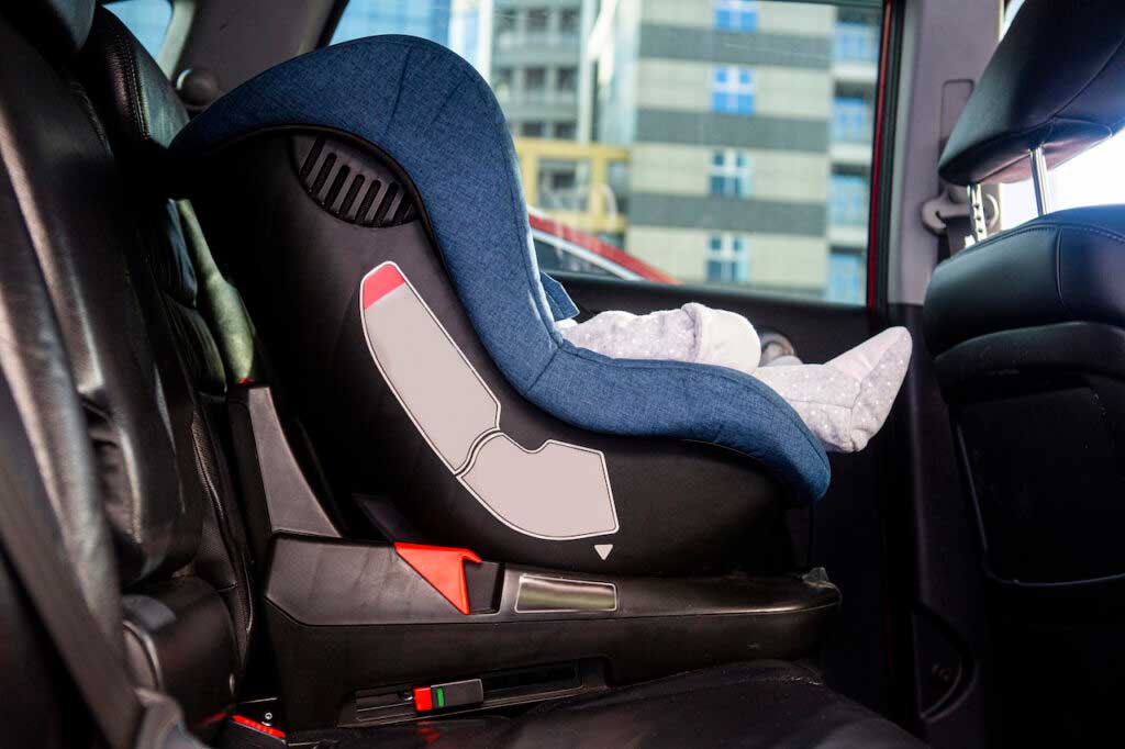 An infant car seat is installed in the back of a car.