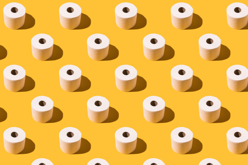 White toilet paper rolls are arranged in rows on a yellow background.