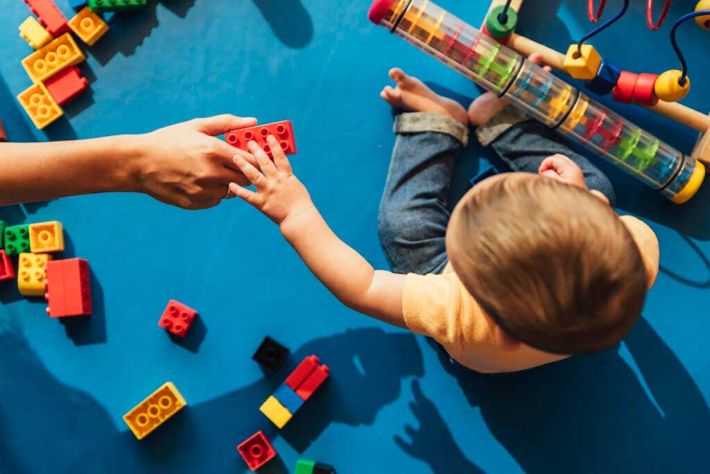 Close up of a parent and baby playing with colorful blocks.