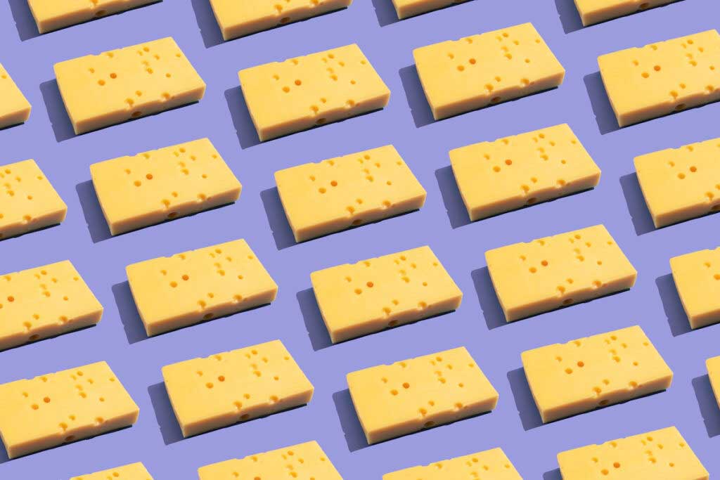 Chunks of cheese in rows on a purple background.
