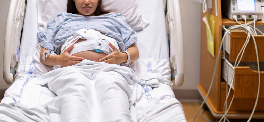 A pregnant person being monitored in a hospital bed before labor.