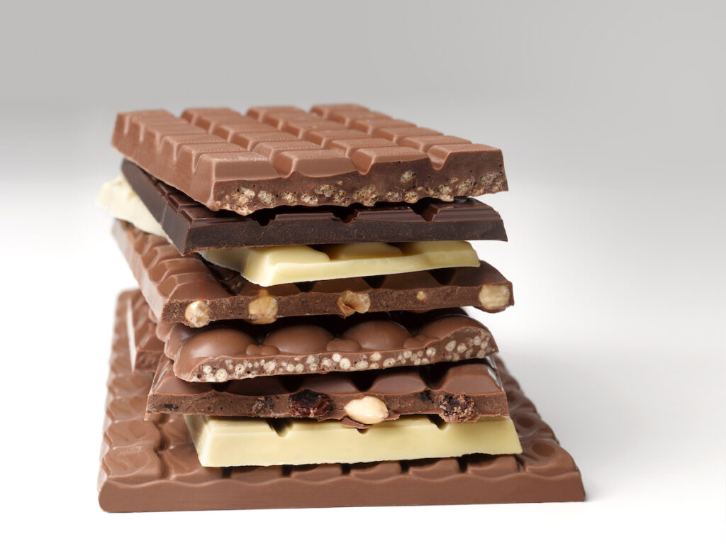 A stack of milk, white, and dark chocolate bars on a white background.