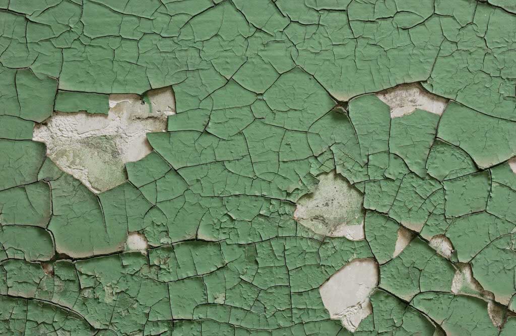 A close-up of green, chipping lead paint.