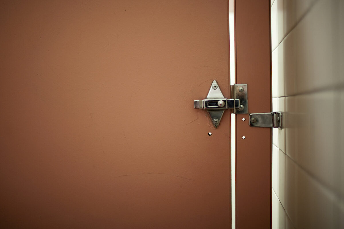 Brown locked bathroom stall door in a public bathroom.