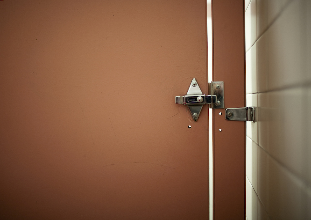 Brown locked bathroom stall door in a public bathroom.